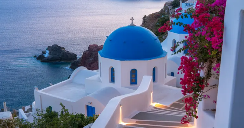 Église aux dômes bleus de Santorin, bougainvilliers et mer Égée — voyage Grèce Oscar Airlines